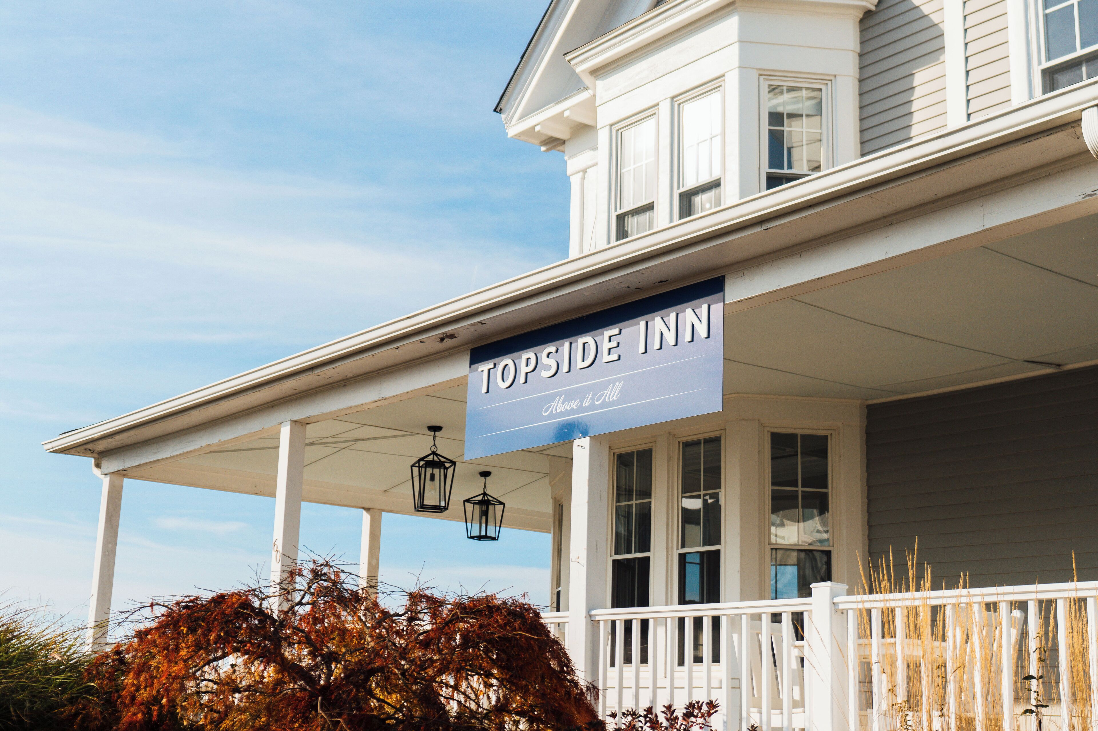Un hôtel avec une enseigne sur le porche indiquant : « Topside Inn, au sommet de tout ».