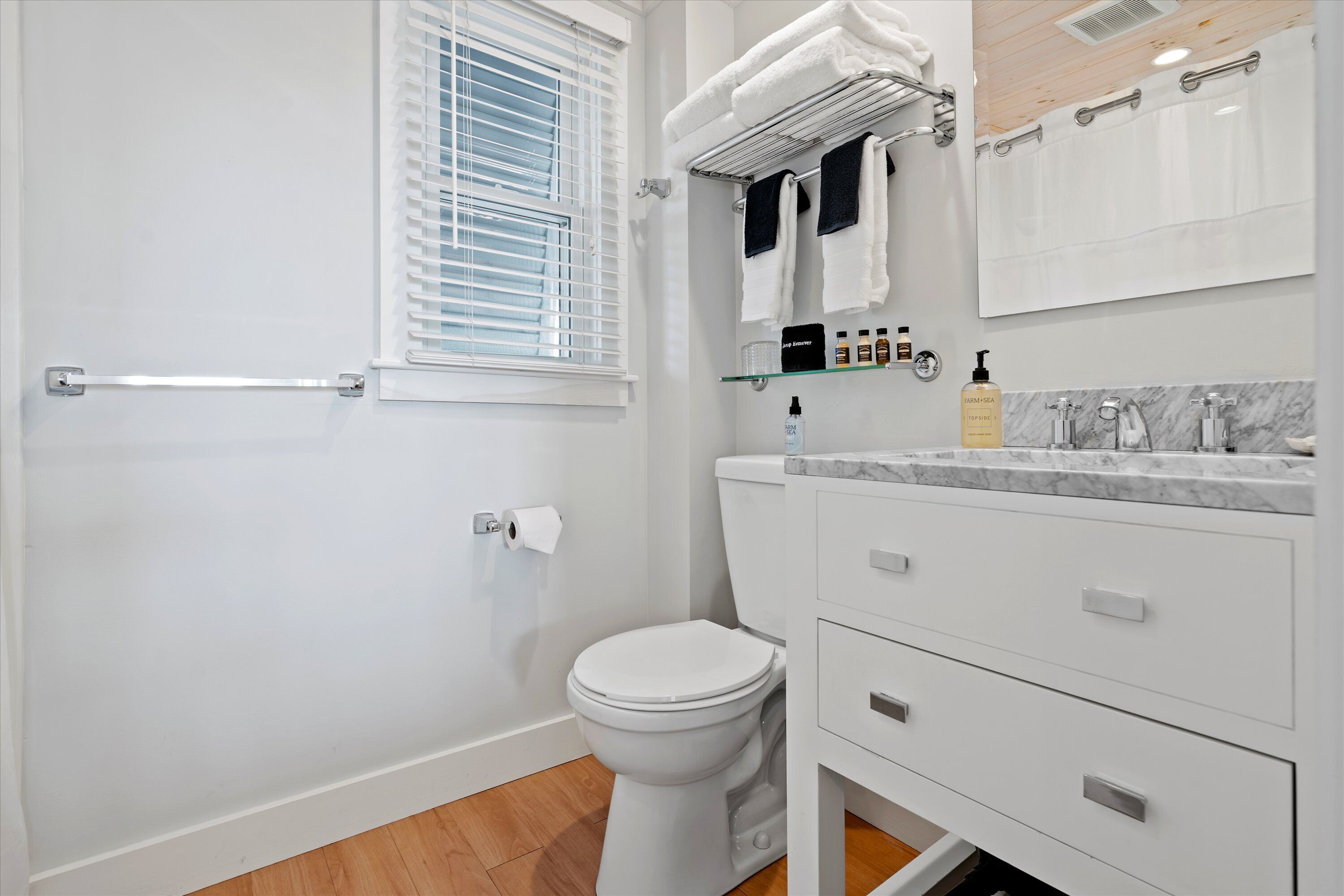 Ein modernes Badezimmer mit Toilette, einer Glastrennwand für Pflegeprodukte und einem Handtuchhalter.