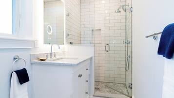 A modern bathroom with a shower, a sink, and a mirror.