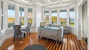 A room with a wooden parquet floor, white wainscoting, large windows with a view, and a glass table with chairs. - Topside Inn (Boothbay Harbor)