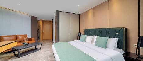 Ein modernes Hotelzimmer mit einem großen Bett, einer Couch, einem Couchtisch und einem Schreibtisch.