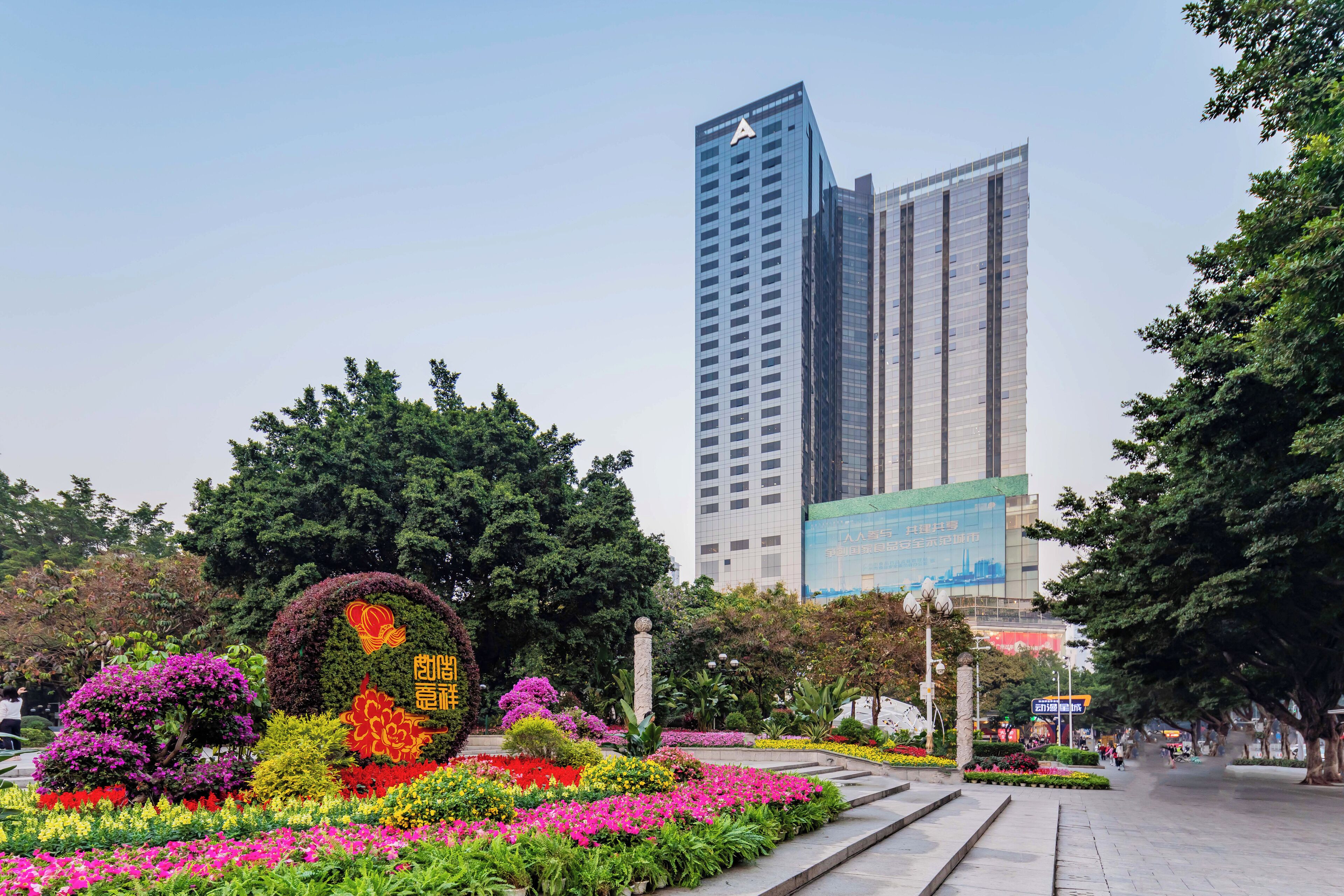 A landscaped garden with colorful flowers and a tall building in the background.
