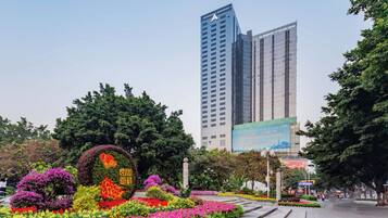 A landscaped garden with colorful flowers and a tall building in the background.