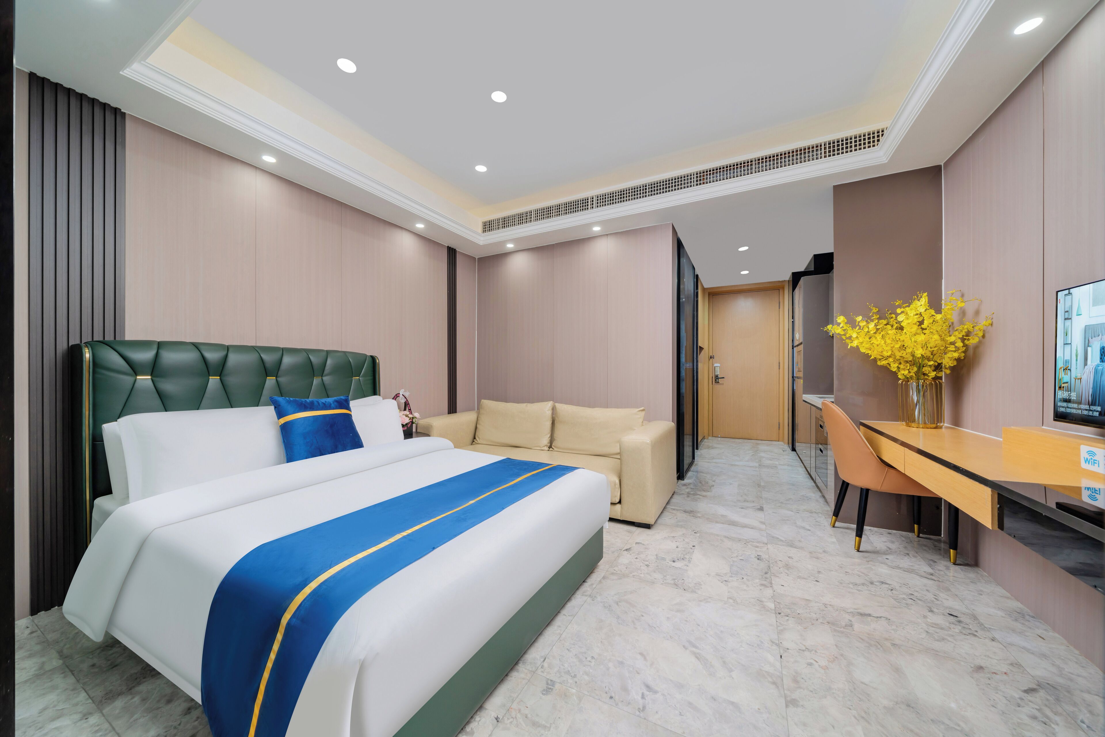 A hotel room with a large bed, a sofa, a desk, and a TV.