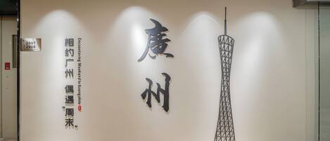 A wall with large Chinese characters and a tall, modern structure.