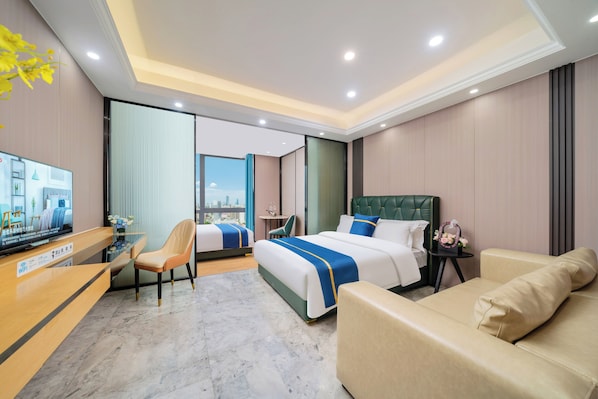 A hotel room with a bed, a sofa, a desk with a computer, and a chair. - Weekend International Apartment- Beijing Rd A-mall (Guangzhou)
