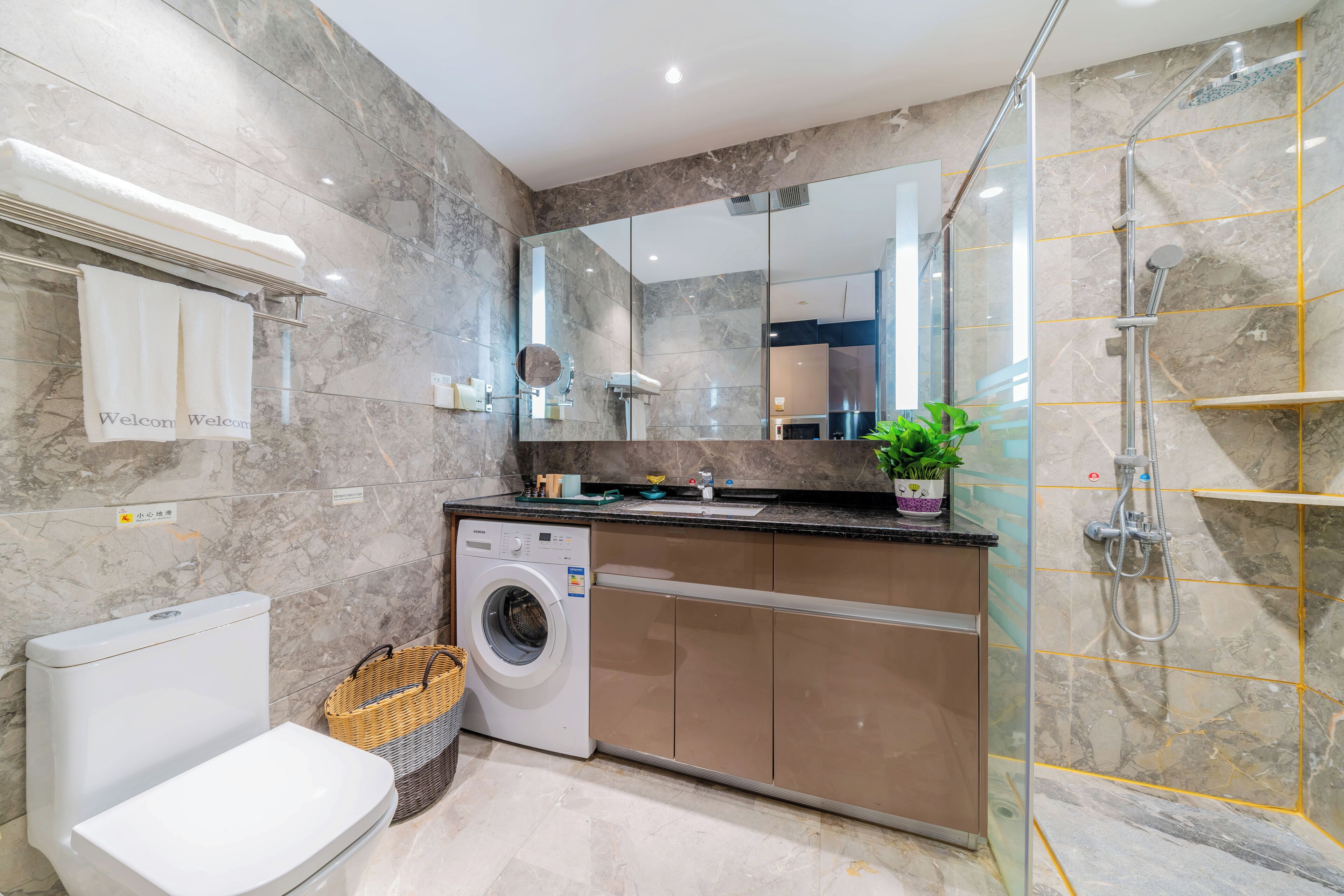 Une salle de bain moderne équipée de toilettes, d’un lave-linge et d’une douche.