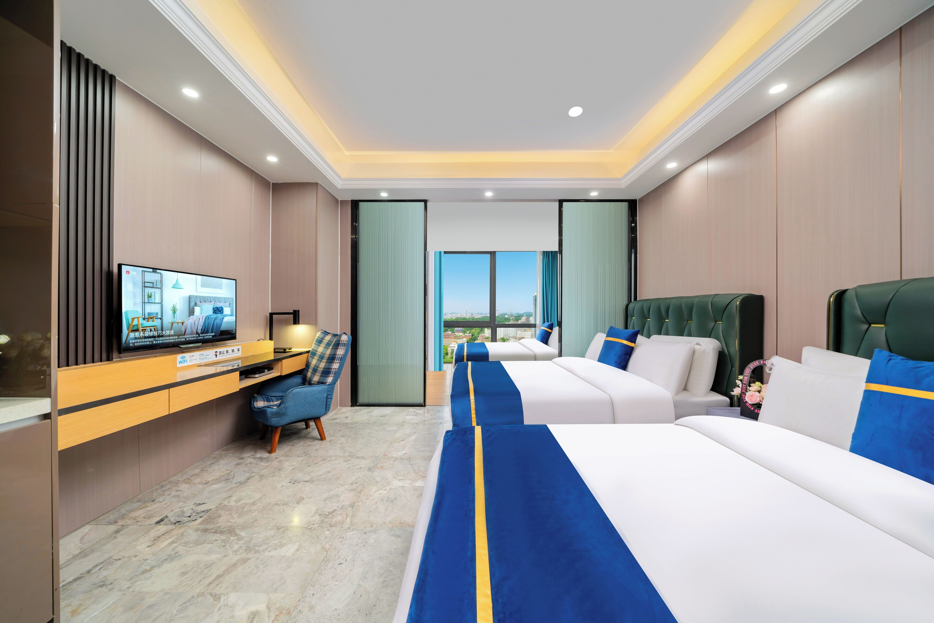 A hotel room with a large bed, a desk with a television, and a view of the city.