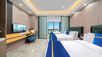 A hotel room with a large bed, a desk with a television, and a view of the city.