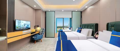 A hotel room with a large bed, a desk with a television, and a view of the city.
