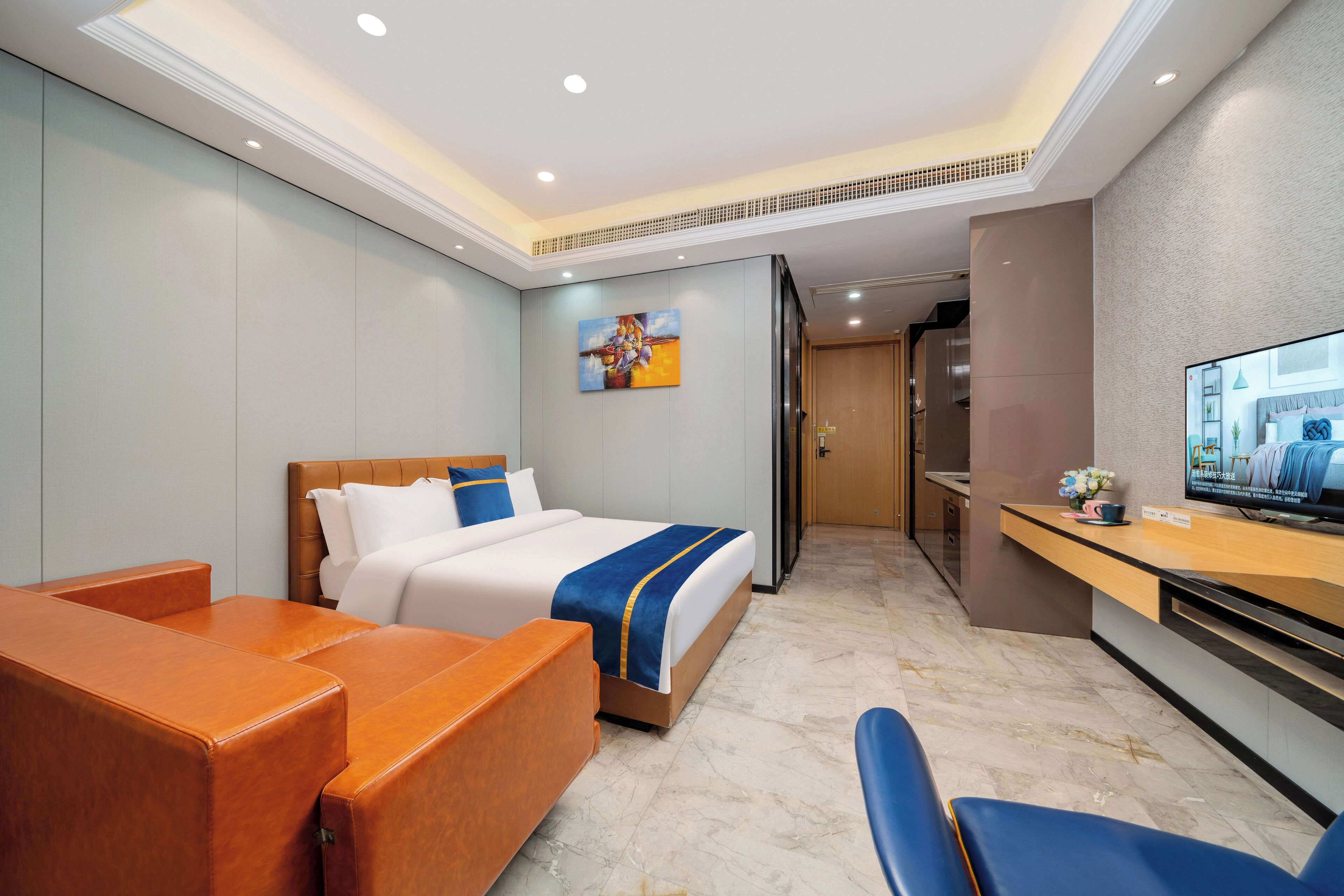 A hotel room with a bed, a desk, a chair, and a television.