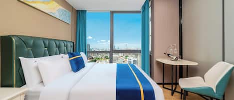 Habitación de hotel con una cama grande, vistas a la ciudad, una mesita y una silla.