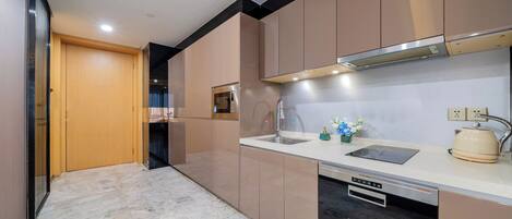Una cocina moderna con horno empotrado, un lavamanos y una tetera sobre la encimera.