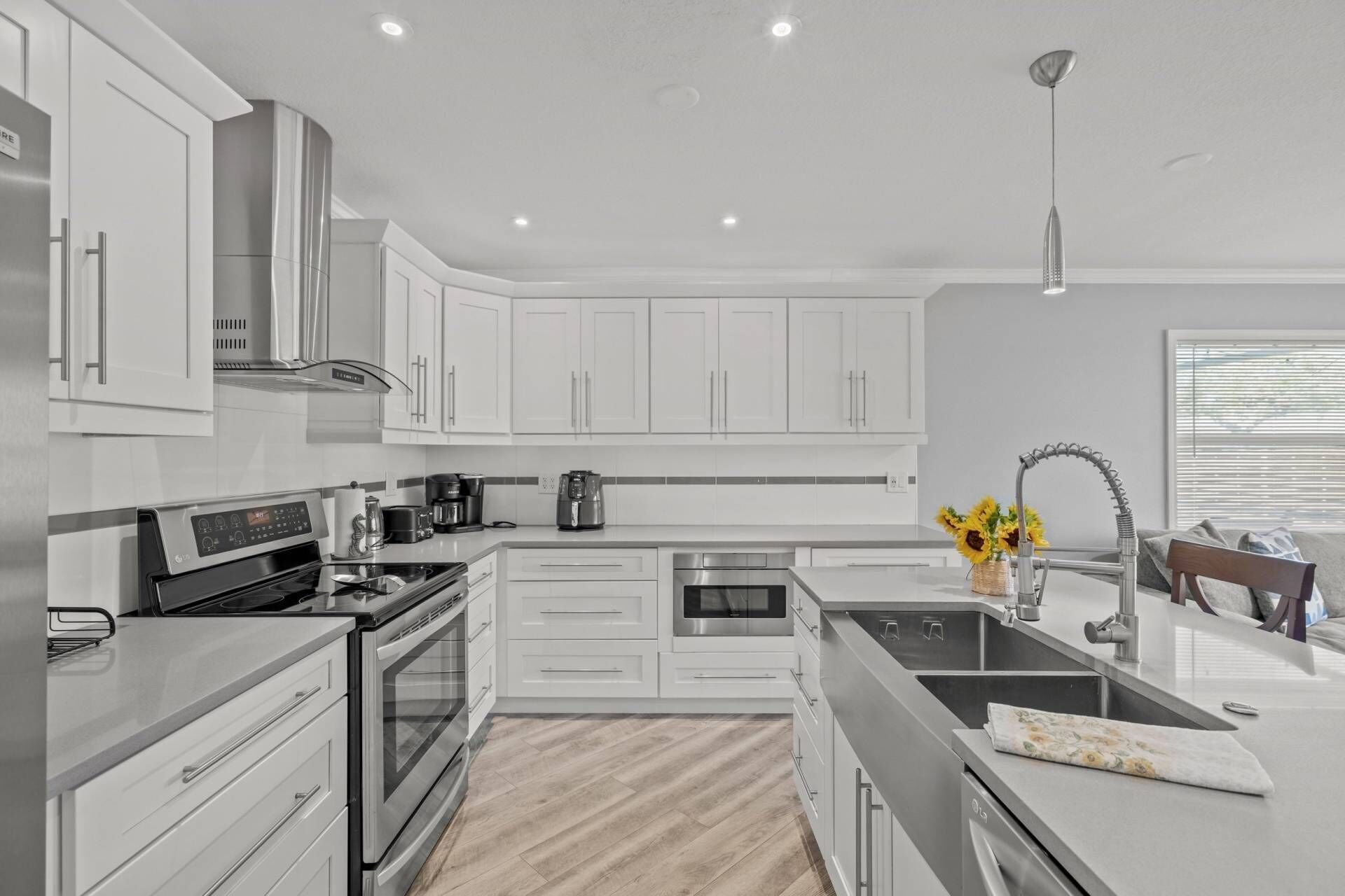 A modern kitchen with white cabinetry, stainless steel appliances, a built-in oven, and a central island with a sink.