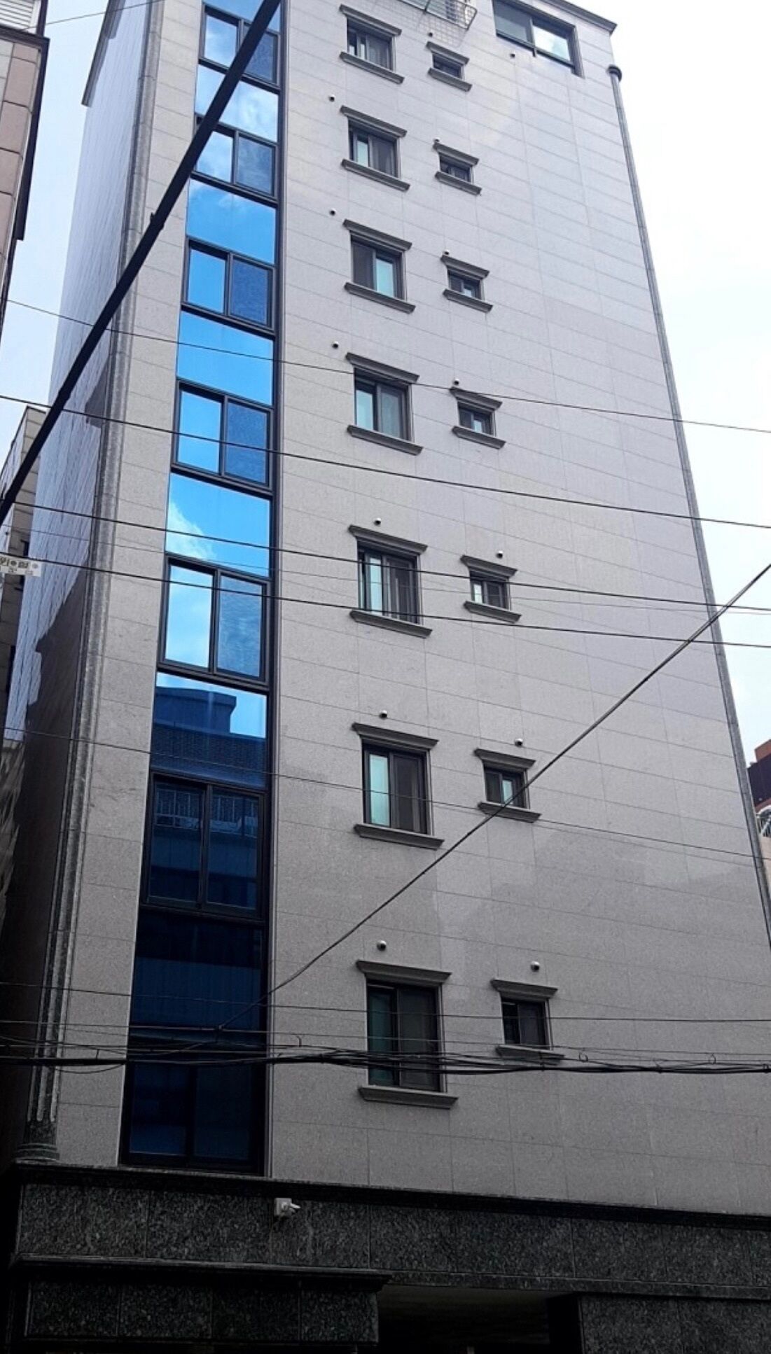 Un edificio alto con molte finestre e una facciata in vetro riflettente.
