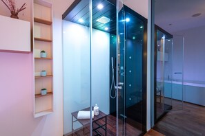A modern bathroom with a glass-enclosed shower, wooden shelves, and a small table with a towel. - Heima Smart - Charme Apartment (Palermo)