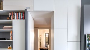 En modern inredning med en bokhylla, en svart matta och en vit högtalare.