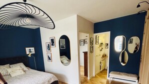 A bedroom with a bed, a large mirror, and a wooden floor. - L'ATTRAPE-COEURS : Charming house 6/7 persons (LA BAULE)