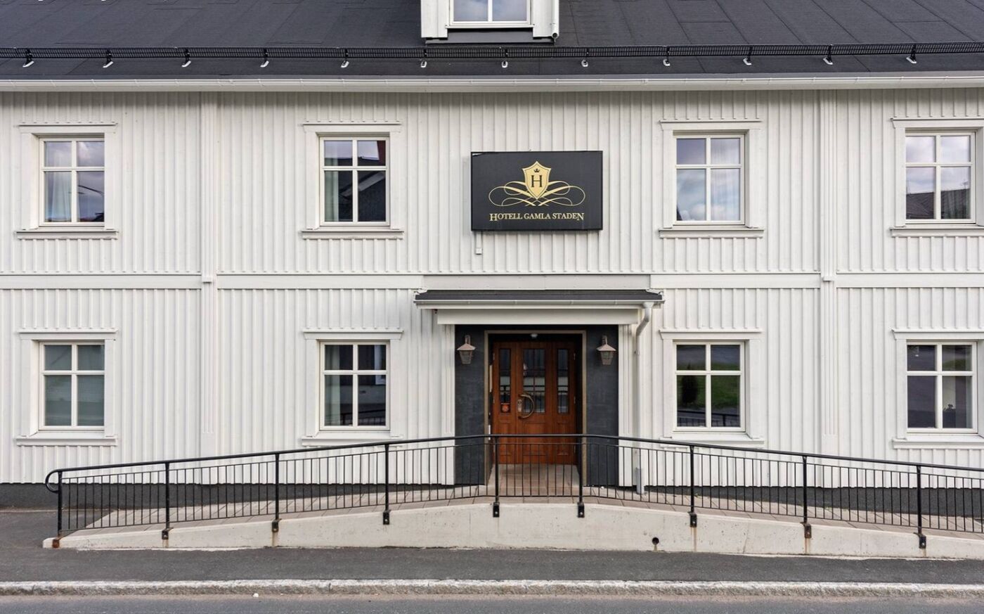 Un edificio blanco con un letrero negro que dice 'HOTEL GAMLA STADEN'.
