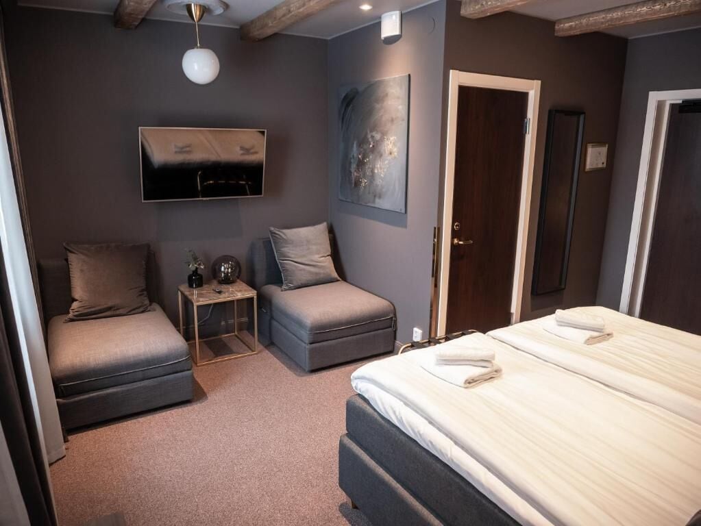 Ein modernes Schlafzimmer mit einem Bett, zwei grauen Sofas, einem kleinen Tisch und einem Bild an der Wand.