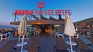 The exterior of Mara Palace Hotel with outdoor seating and a view of the mountains. - Mara Palas Hotel (Fethiye)