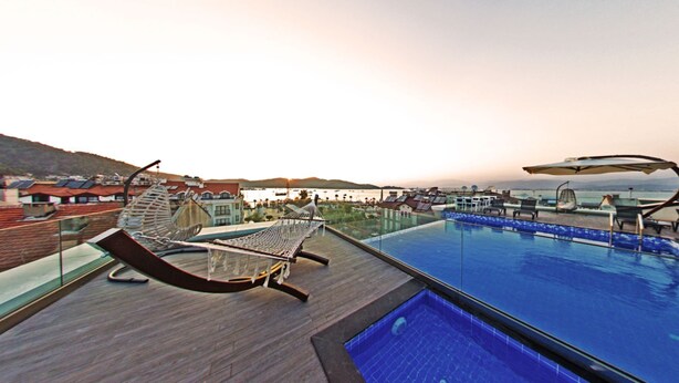 A rooftop pool area with lounge chairs and a glass barrier. - Mara Palas Hotel (Fethiye)