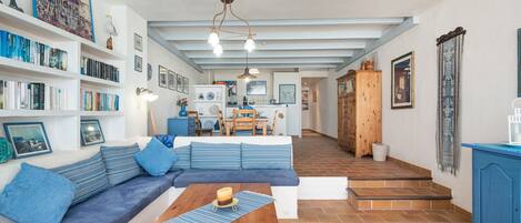 A spacious living area with a large sofa, wooden coffee table, and a kitchen in the background.