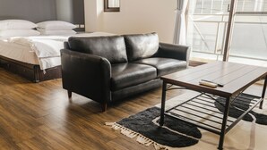 Un dormitorio moderno con un sofá de cuero, una mesa de centro de madera y una cama con ropa blanca.