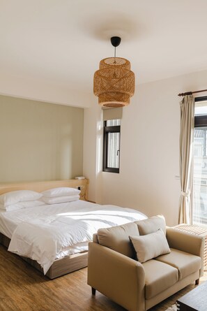 Une chambre à coucher avec un lit, un canapé, une fenêtre et un luminaire suspendu.