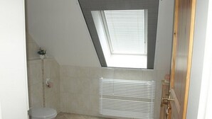 A bathroom with a skylight, toilet, radiator, and tiled floor.