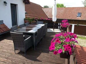 An outdoor patio with a table and chairs, surrounded by potted plants and a wooden fence.
