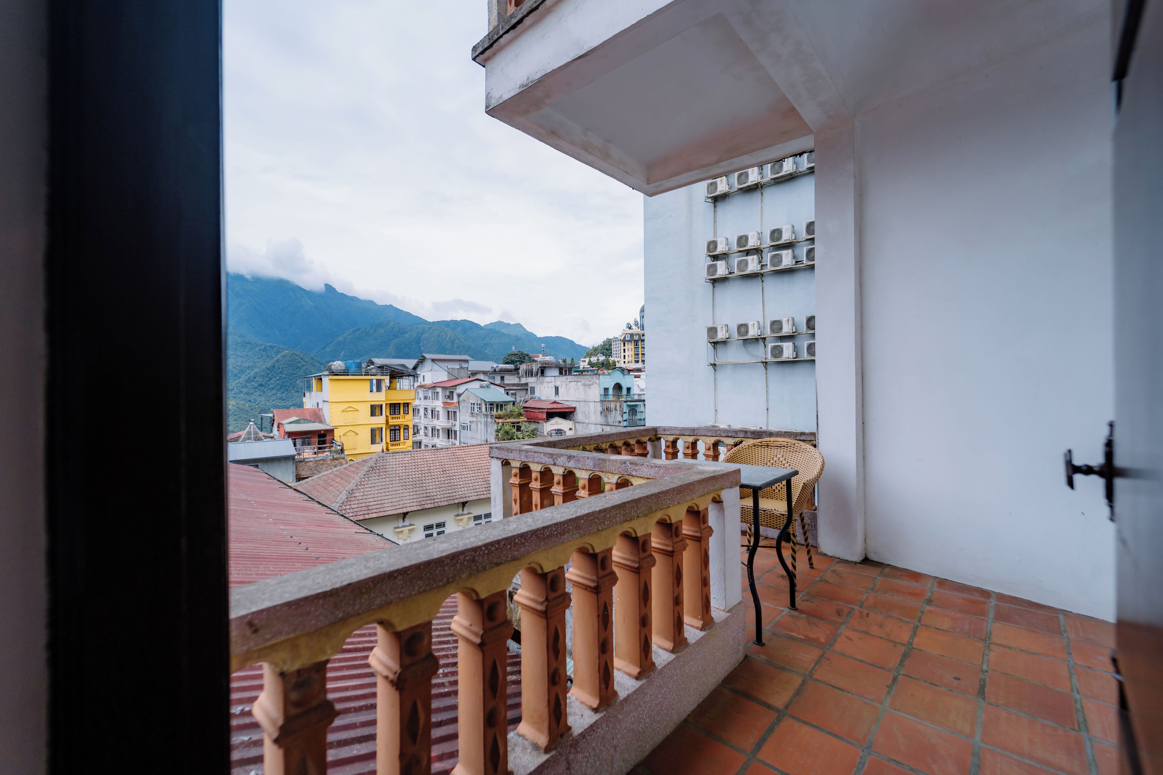 Un balcón con vistas a edificios y montañas.