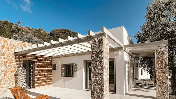 Ein modernes Haus mit Pool, Steinmauern und einer Pergola.