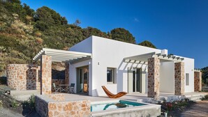 Une maison moderne dotée d’une piscine, de piliers en pierre et d’une pergola.