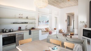 Une cuisine moderne dotée d’appareils électroménagers intégrés, un coin repas avec une table et des chaises, et un espace de vie comprenant un canapé et une cheminée.