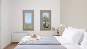 Une chambre avec deux fenêtres, un lit, une table de chevet avec une lampe et un radiateur.