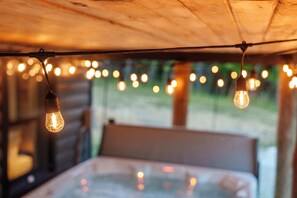 Una cama con cabecera, una ventana con cortinas y luces colgantes.