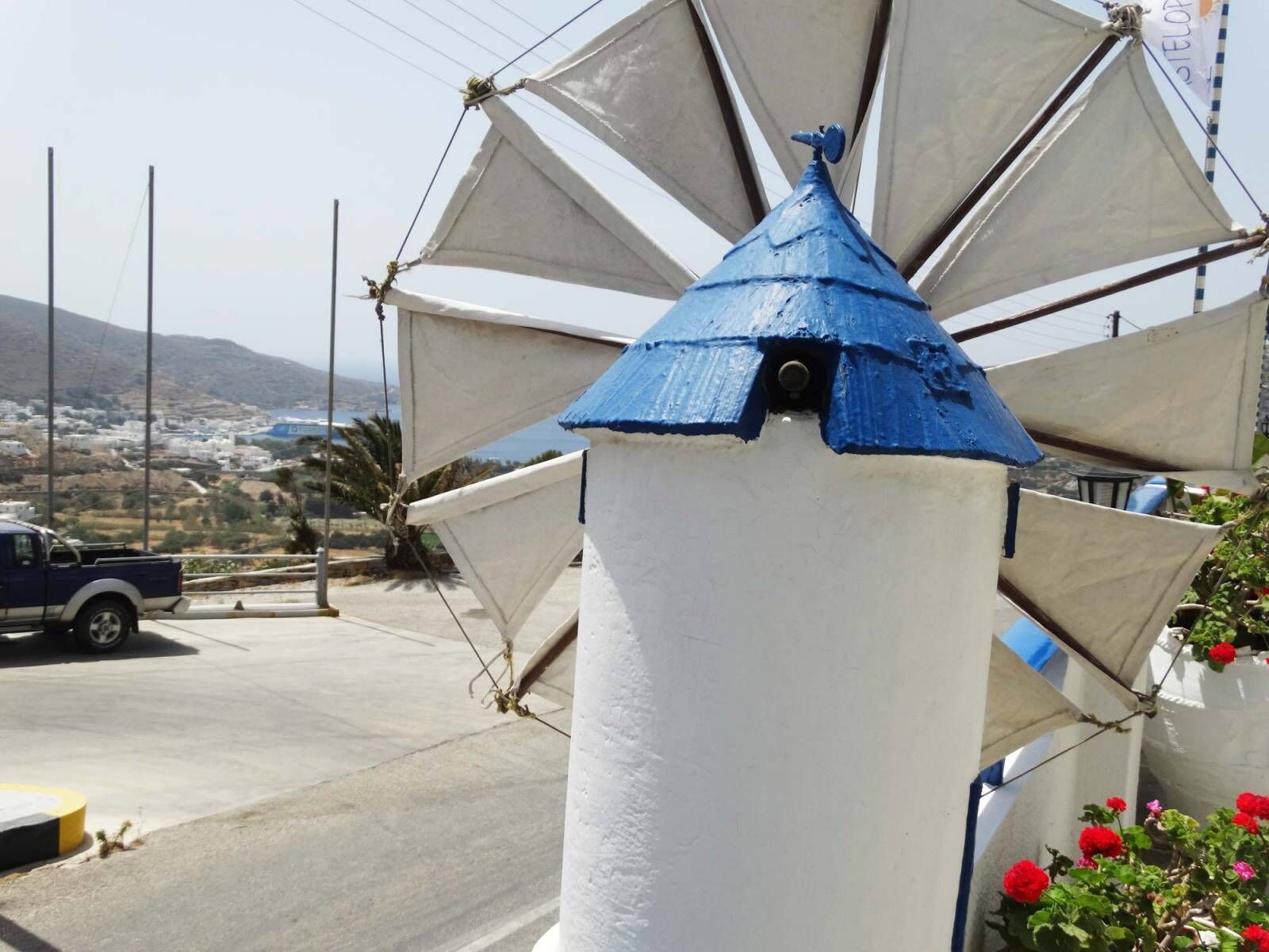 Un phare avec un toit bleu et des murs blancs, entouré de voiles blanches.
