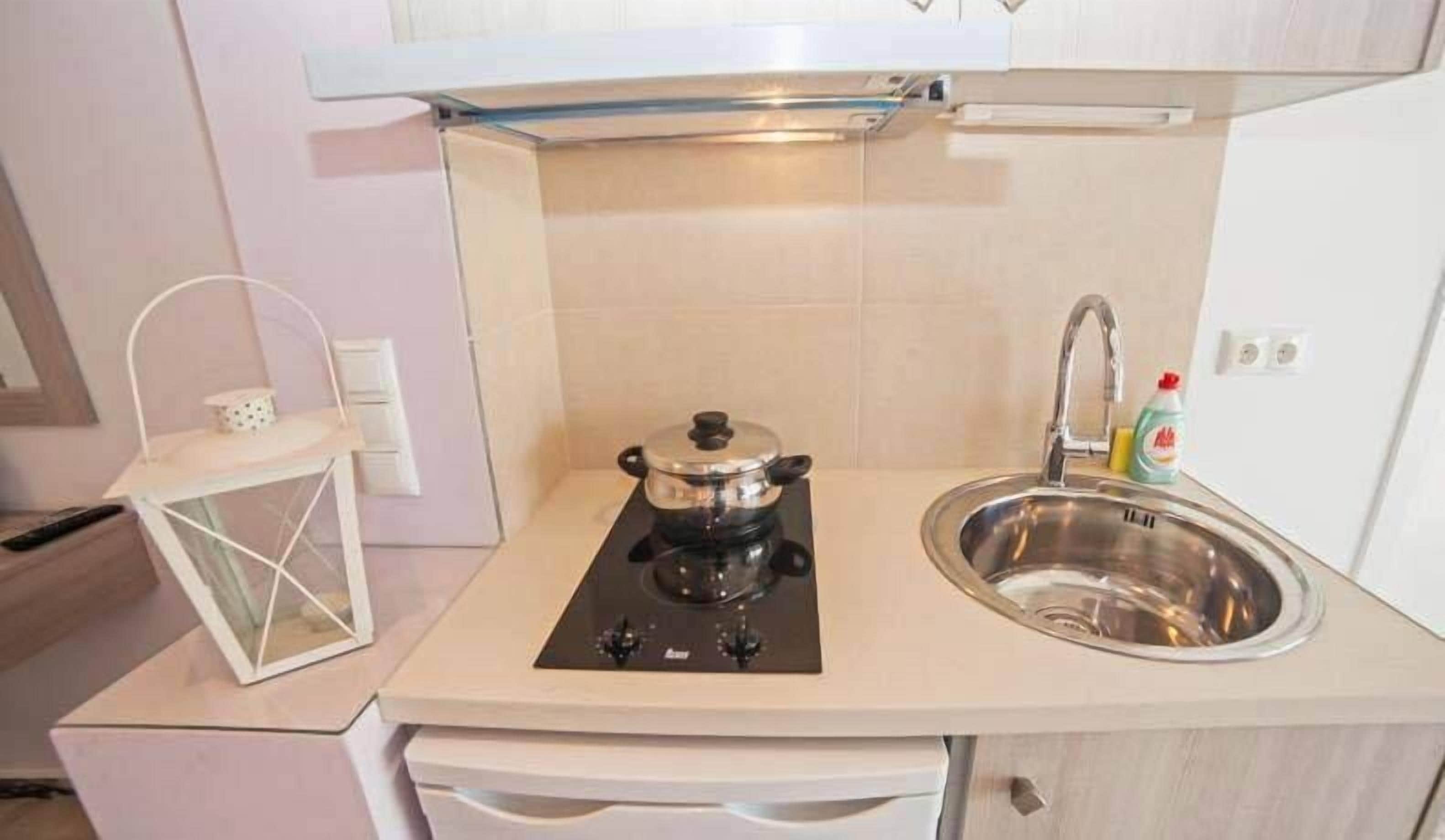 Una kitchenette compacta con estufa, pileta y un mueble pequeño.
