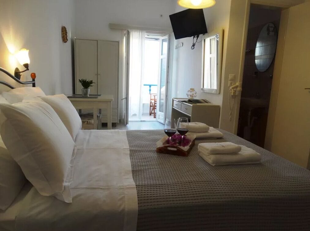 Une chambre d’hôtel avec un lit, un bureau, une chaise, une télévision et une porte de salle de bain.