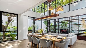 A modern dining area with a wooden table, grey chairs, and a sofa. - Elio Villa by Kozystay (Jimbaran)