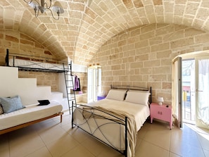 Une chambre avec un lit superposé, un lit simple, un escalier, une armoire rose et une grande fenêtre.