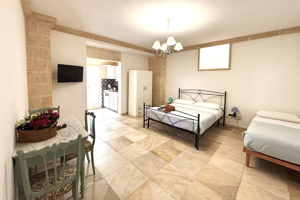 Une chambre à coucher avec un lit, une table de chevet, une chaise et un téléviseur fixé au mur.