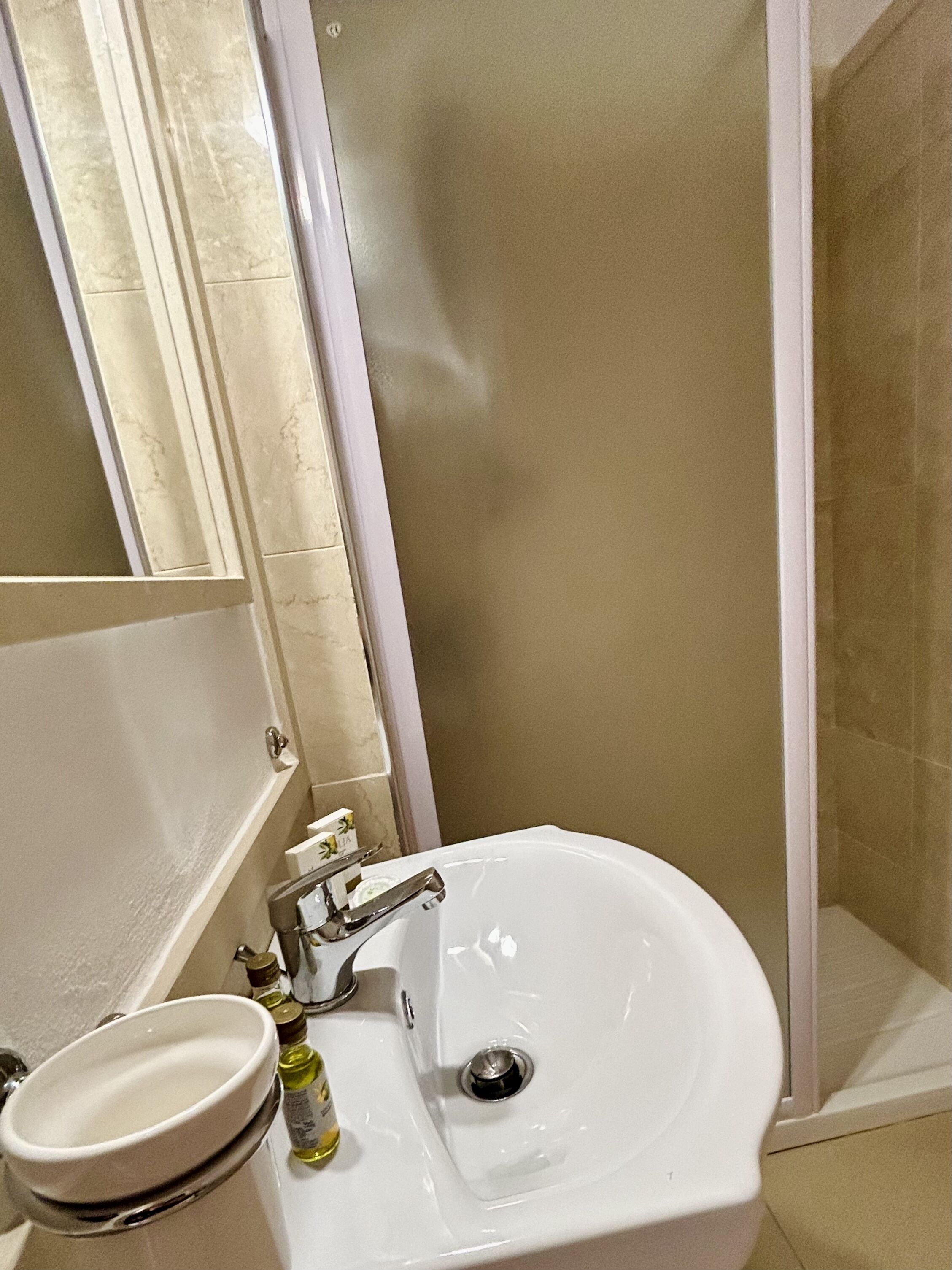 Une salle de bain avec un lavabo blanc, un miroir et un espace douche.
