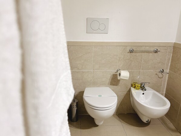 A bathroom with a toilet, bidet, and a towel rack.