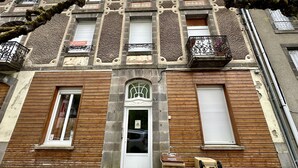A building with a wooden facade, a central entrance, and multiple windows with shutters. - Le MB 9 Le Mont Dore 8pers (Mont-Dore)