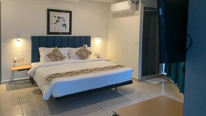A modern bedroom with a large bed, bedside lamps, a ceiling fan, and an air conditioning unit. - Pam Inn Hotel Vadodara (Vadodara)