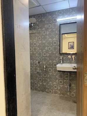 A bathroom with patterned tile walls, a sink, and a mirror.