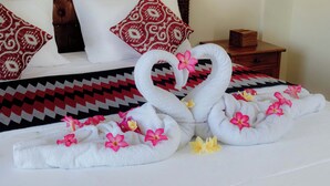 Una cama bien hecha con una colcha estampada, dos almohadas decorativas y una mesita de noche de madera con una caja.