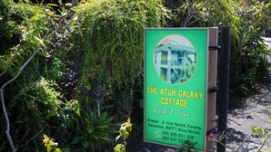 Letrero de The Atuh Galaxy Cottage con información de contacto y una foto del edificio.